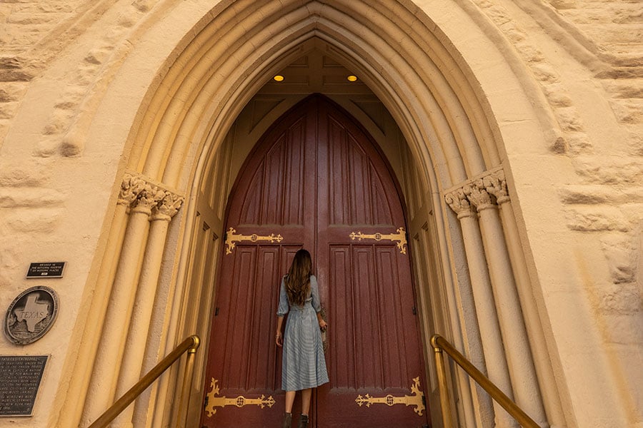 a woman walks up to the cathedral doors