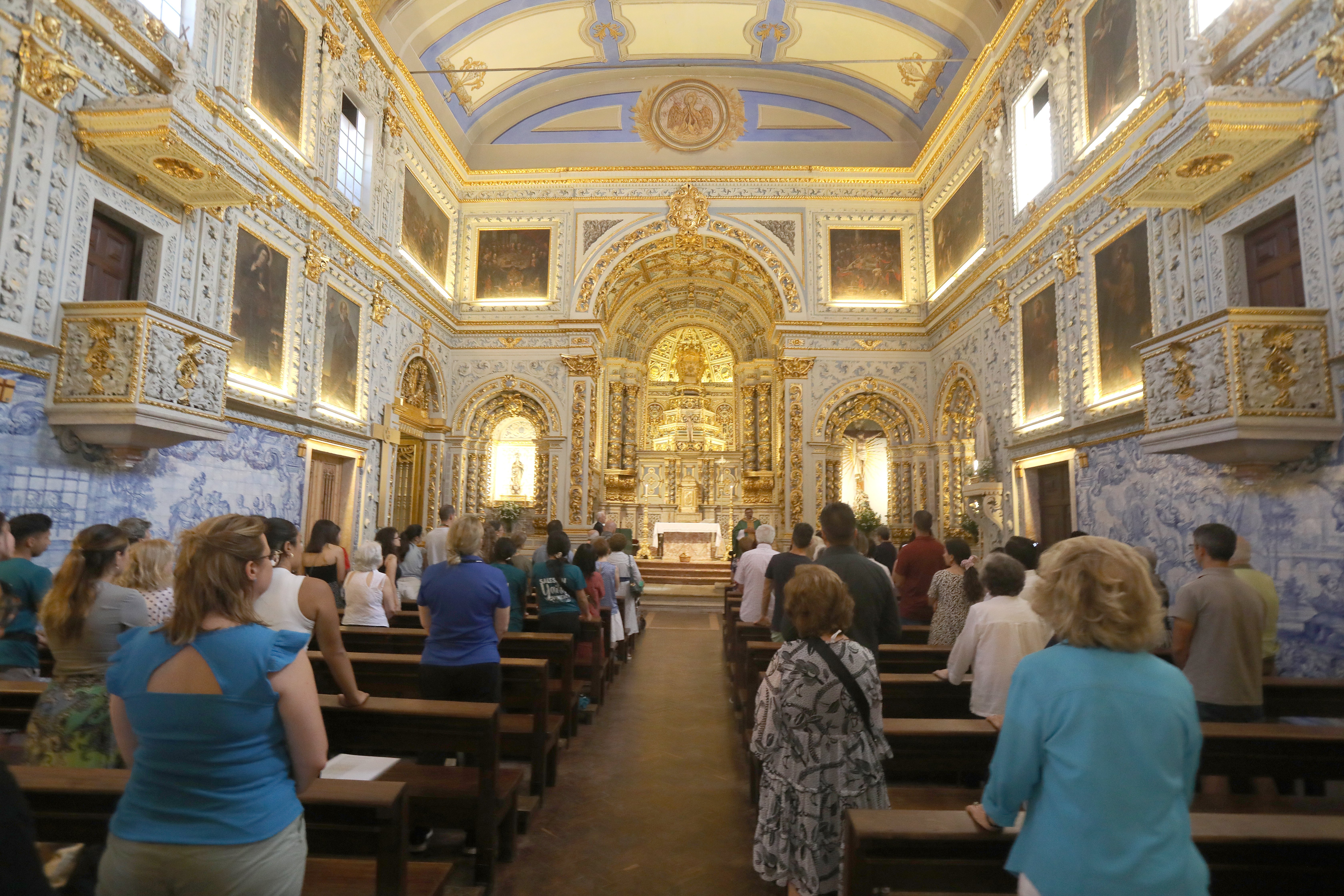 worshippers stand before pews in a beautiful church hall in Lisbon, Portugal