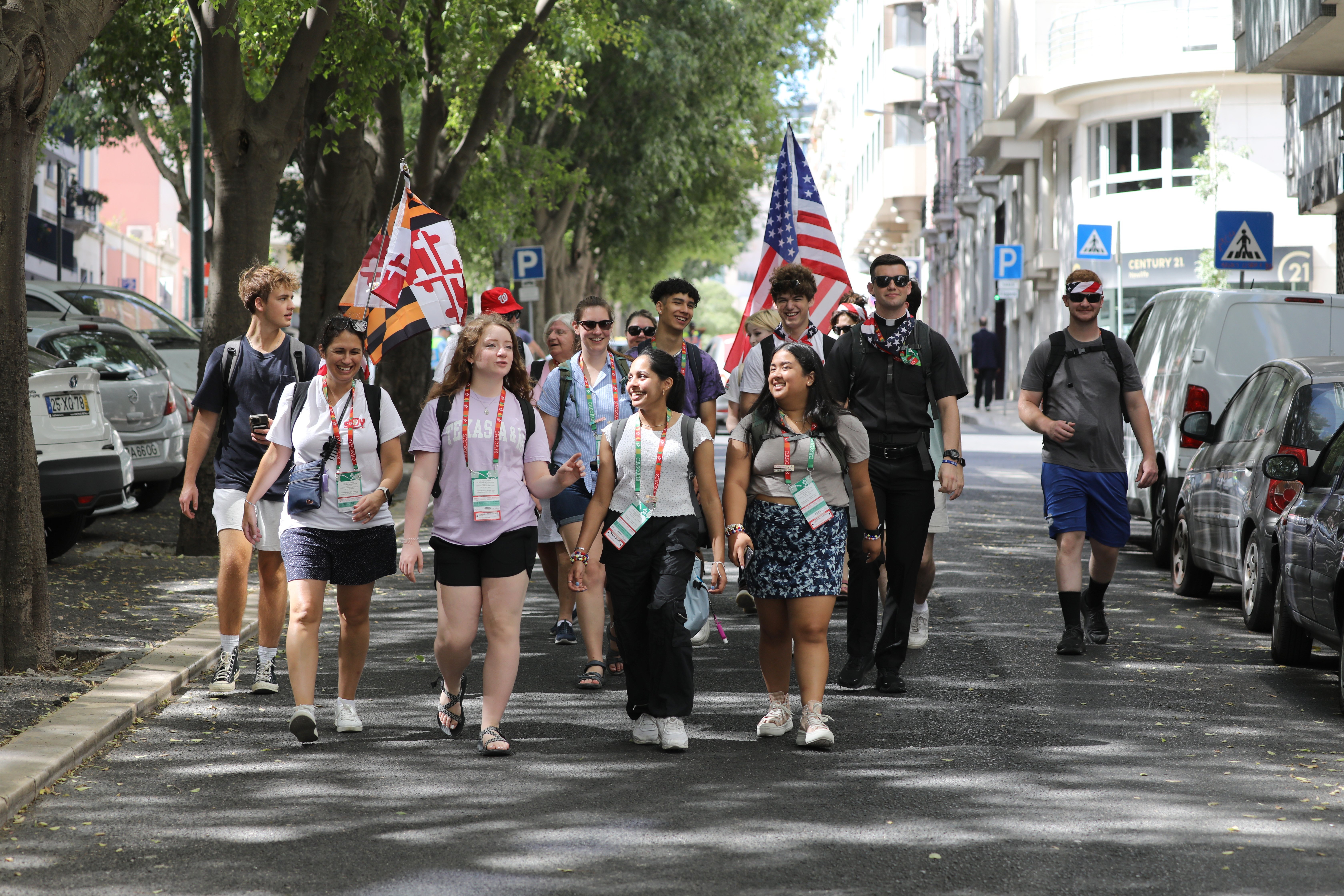 American pilgrims walk the streets of Lisbon in a group bearing USA flags