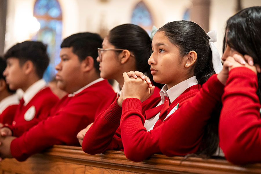 students kneel in prayer