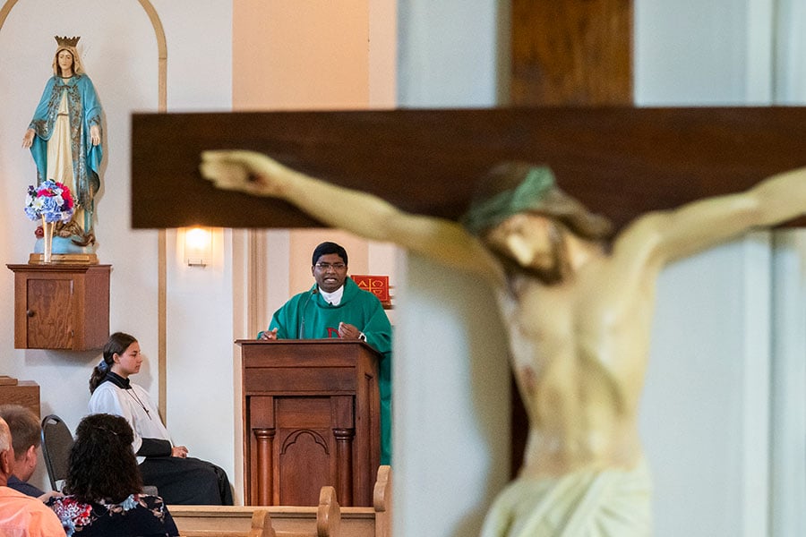 Crucifix in foreground, Fr. Bose at ambo in background