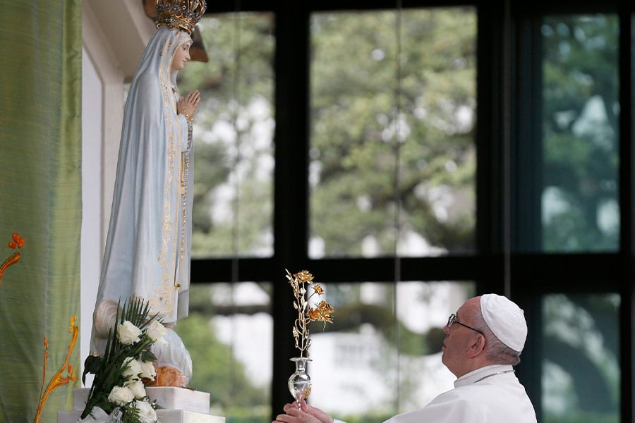 Pope Francis places flowers near a statue of Mary as he prays in the Little Chapel of the Apparitions at the Shrine of Our Lady of Fatima in Portugal, May 12, 2017. The Vatican said Pope Francis will consecrate Russia and Ukraine to the Immaculate Heart of Mary March 25, 2022.