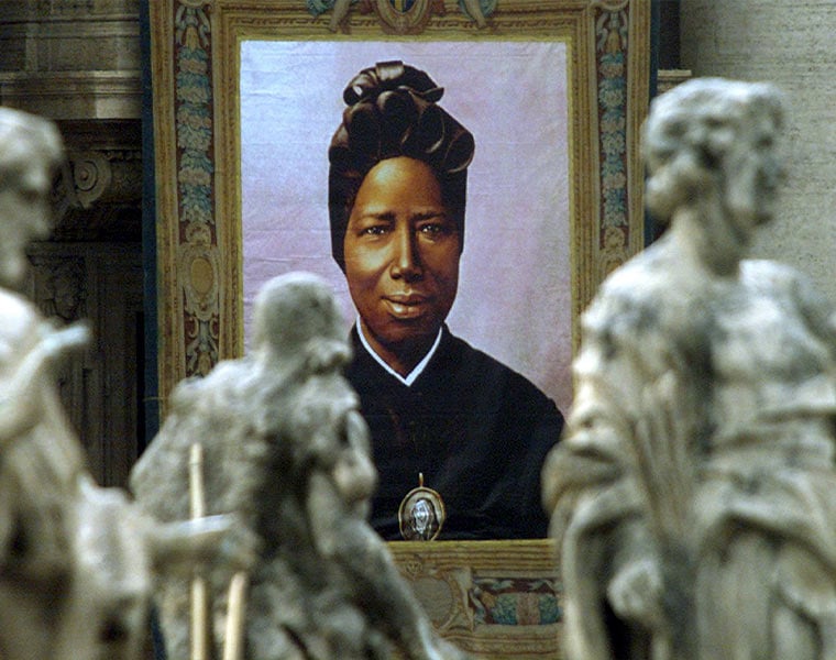 An image of Josephine Bakhita, a former Sudanese slave who became a nun, hangs from the facade of St. Peter's Basilica Oct. 1. She was canonized by Pope John Paul II along with 120 Chinese martyrs and U.S.-born Mother Katharine Drexel.