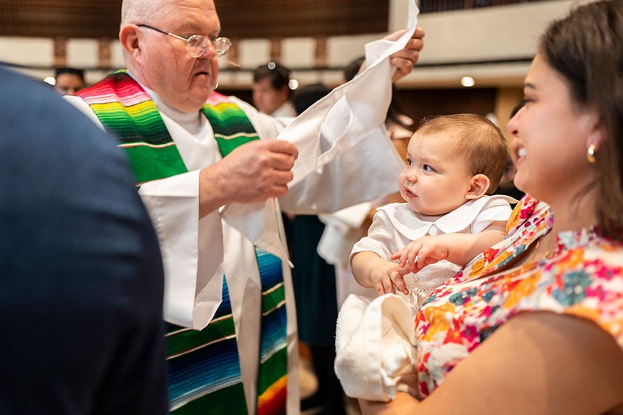 Mom holds baby as white garment is placed on baby