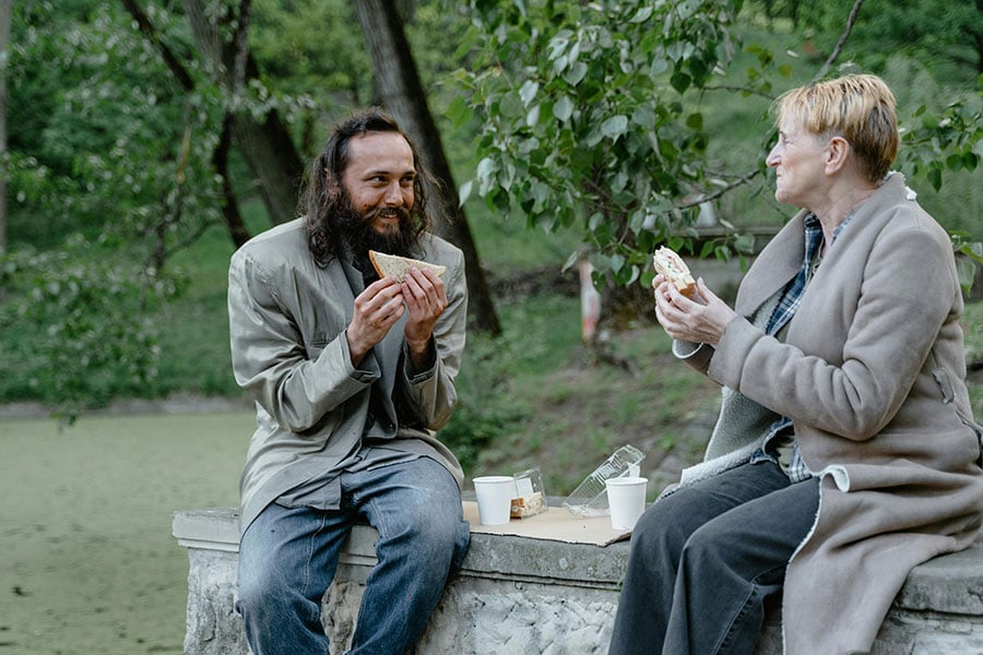 homeless man and woman eating sandwich
