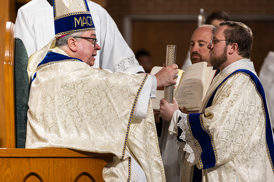 Bishop Olson handing Blake the Gospels