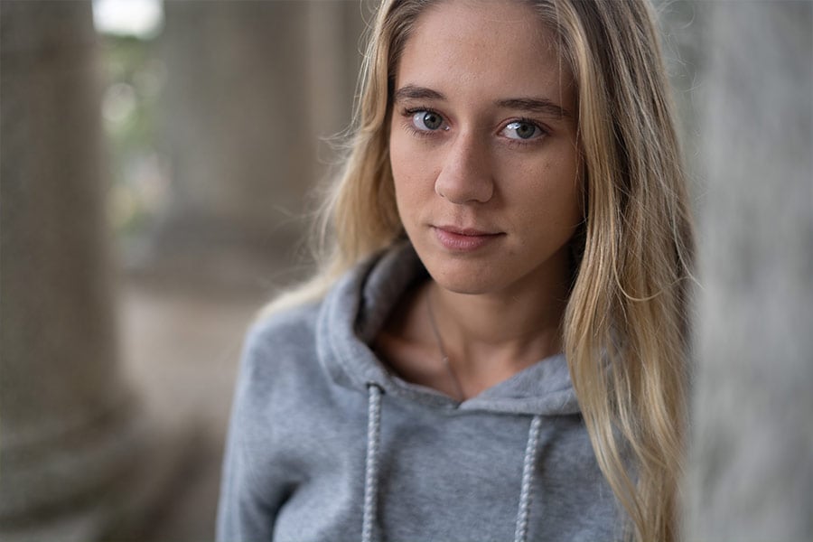 Close-up portrait of a young blonde woman in a grey hoodie.