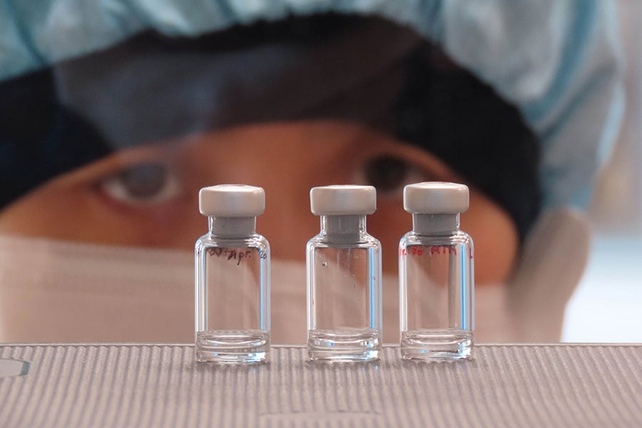 scientist checks quality control of COVID-19 vaccine vials