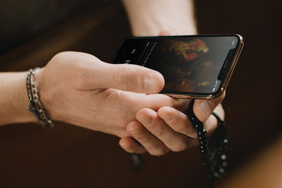 hand holding phone and rosary