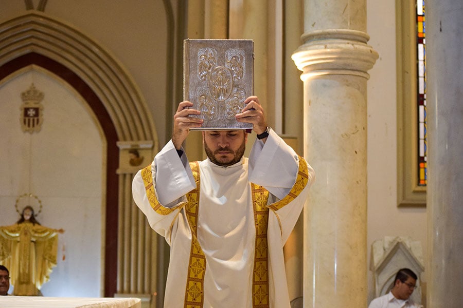 man holds book of the Gospels