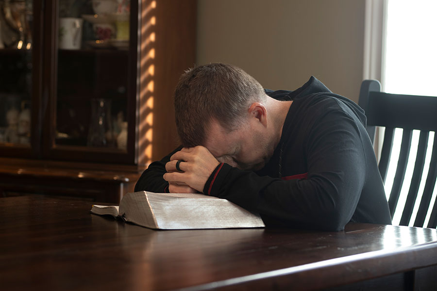 man with head on bible