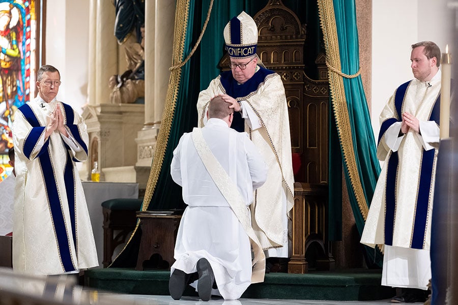 Isaac McCracken kneels in front of Bishop Olson