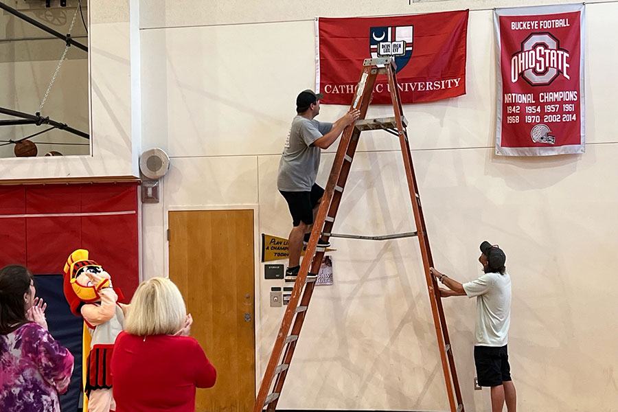 men on ladder hanging flag at gym