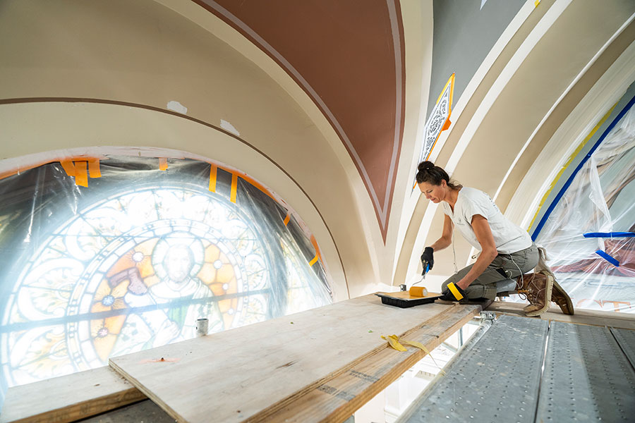 woman paints church arch