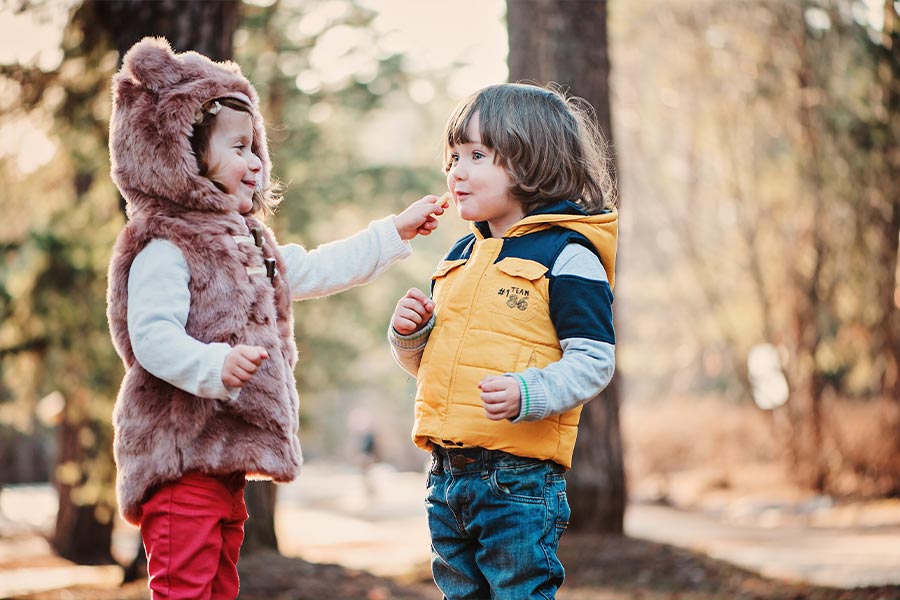 Toddler girl sharing cookie with her friend on the walk (Copyright (c) 2015 Maria Evseyeva/Shutterstock)