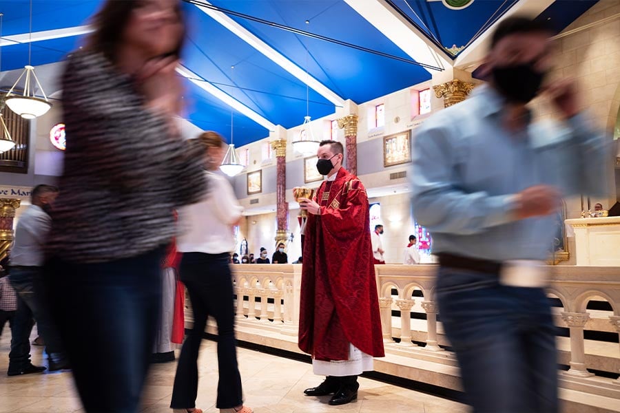 A slow camera shutter shows motion blur of parishioners as they move after receiving the Eucharist from Fr. Jason Allan, center, and his assistants during the celebration of his first Mass at St. Elizabeth Ann Seton in Keller, on May 23, 2021. (NTC/Ben Torres)