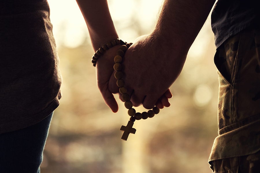 A Catholic couple hold hands.