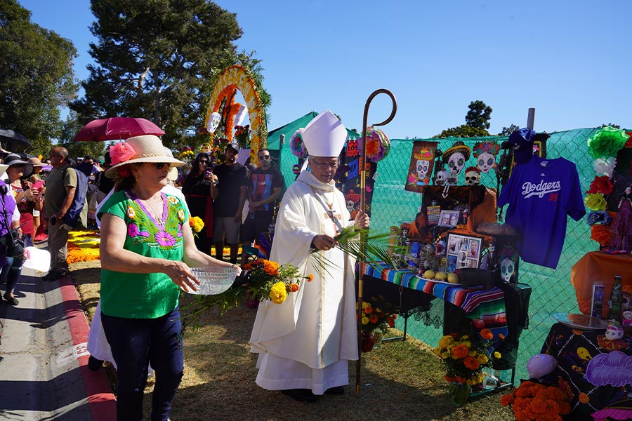 Los Angeles Auxiliary Bishop Alejandro D. Aclan blesses items with holy water during the Dia de los Muertos (Day of the Dead) celebration at Santa Clara Cemetery Oct. 26, 2019, in Oxnard, Calif. Day of the Dead is a Mexican custom traditionally observed Nov. 1 and 2 to remember family and friends who have died. (CNS photo/Sarah Yaklic, courtesy Archdiocese Los Angeles)