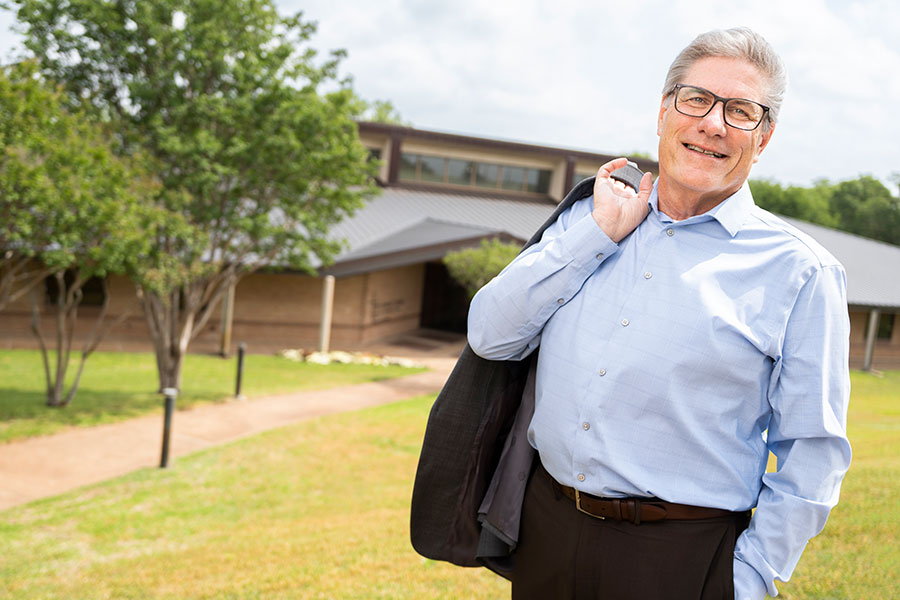 a smiling Don Wagner stands outside the Catholic Center with his suit jacket thrown over his shoulder