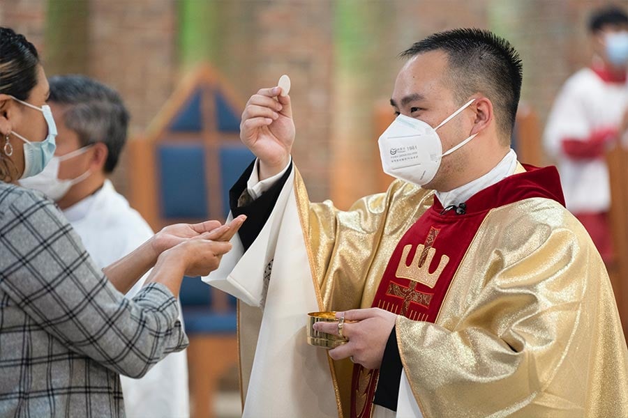 Father Linh Nguyen gives Holy Communion to a parishioner at his first Mass as a priest on May 23, 2021 at Christ the King Parish in Fort Worth. (NTC/Jayme Donahue)