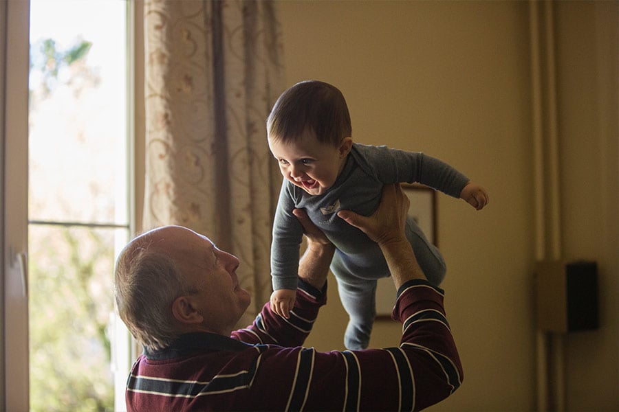 A grandfather lifts-up his grandson.