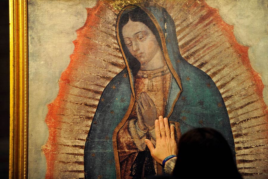 A woman lays her hand on a traveling missionary image of Our Lady of Guadalupe during a visit by the replica to St. Louis Church in Pittsford, N.Y. The digital image is a reproduction of the image left on the tilma of St. Juan Diego in present-day Mexico City in 1531. (CNS photo/Mike Crupi, Catholic Courier)