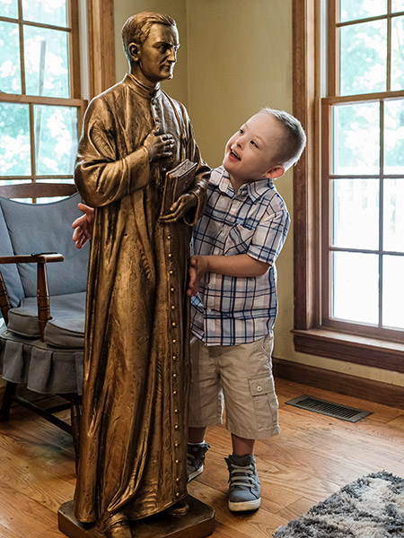 Mikey Schachle, 5, examines a statue of Father Michael McGivney