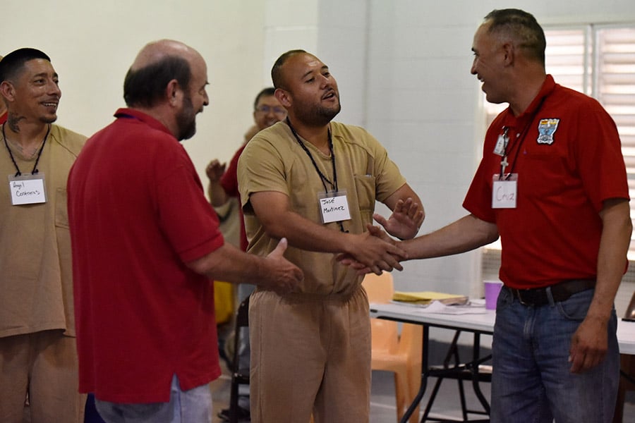 Inmates shake the hand of Cruz Jimenez after a singing performance at the Kolbe Prison Ministries retreat.