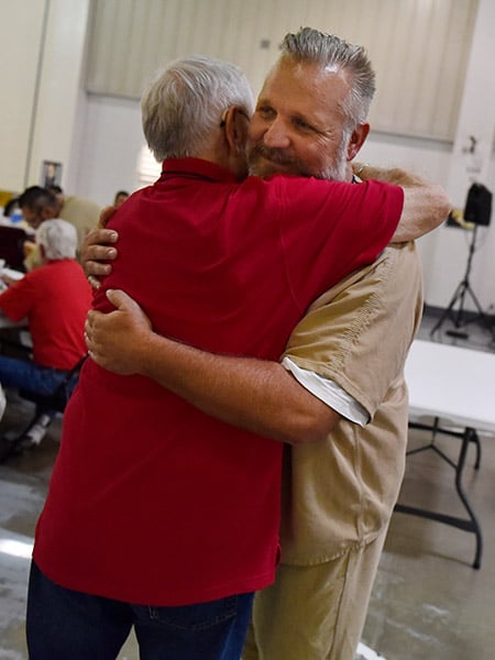 An inmate named Sammy hugs a Catholic volunteer.