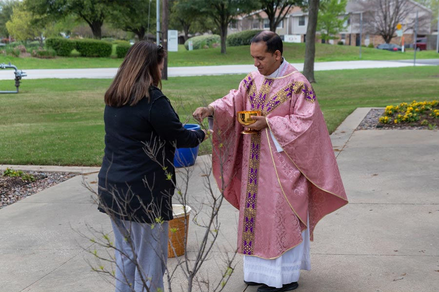 MARCH 2020 - Father Sojan George distributes the Holy Eucharist outside St. Francis of Assisi Church in Grapevine on March 21, 2020. “Stay-at-home” orders put a stop to the public distribution of the Eucharist the following week.  (NTC/Joseph Barringhaus)