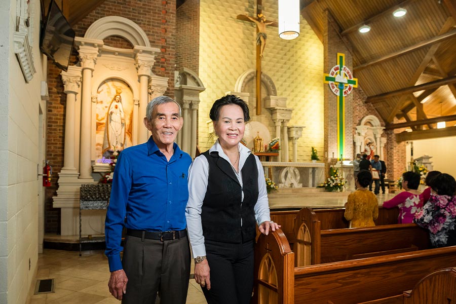 Joe and Mary Pham. Their devotion to the Blessed Mother inspired them to donate the Marian statue behind them to Christ the King Parish in Fort Worth. (NTC/Ben Torres)