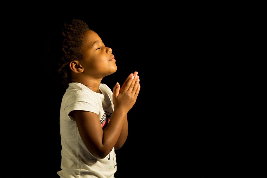 A young child prays to God. (iStock)