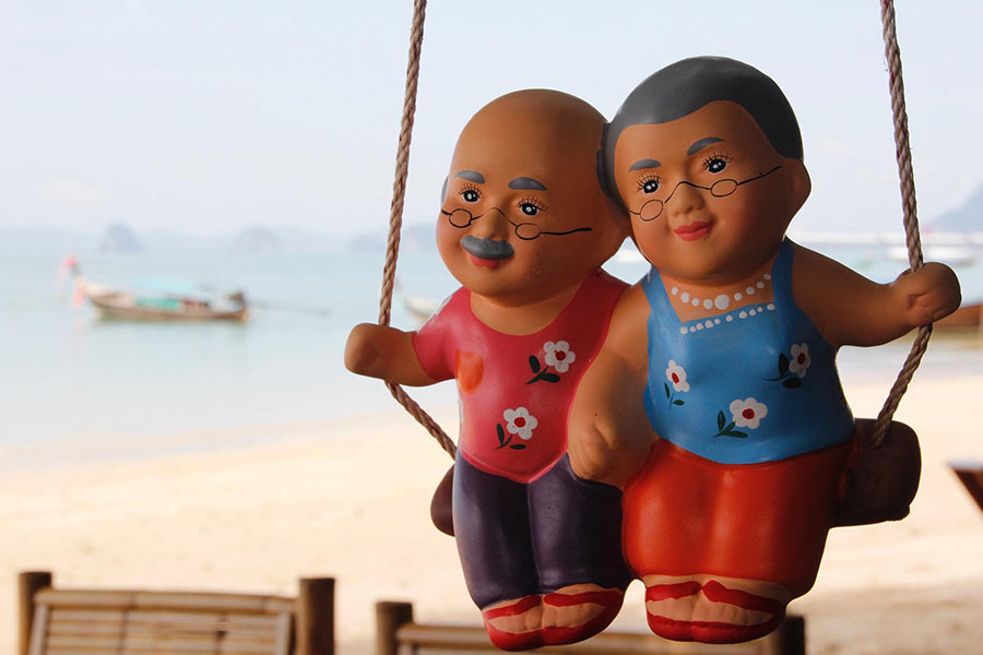 Husband and wife figurines sitting on swing.