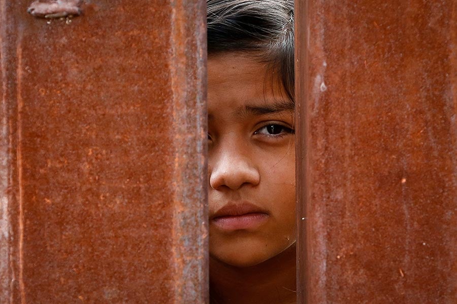 A Mexican girl peers through the fence during Mass at the international border.