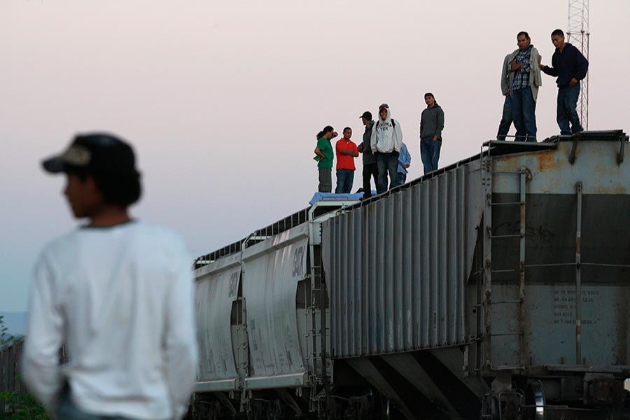 Central American migrants stand atop freight cars while waiting for the freight train.