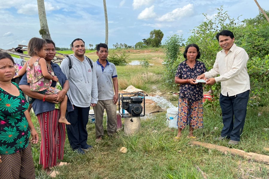 people standing around a water well.
