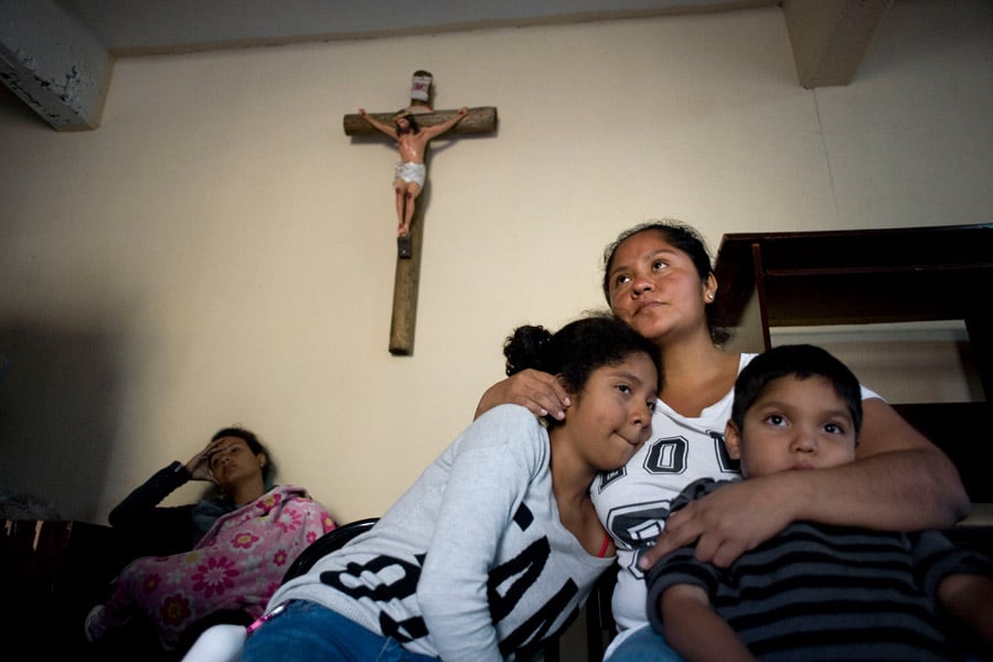 A mother and her two children rest at a Catholic migrant shelter.