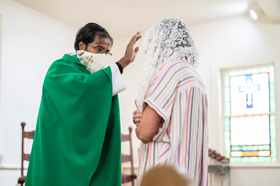 Father Vijaya Mareedu blesses a woman at the Sept. 4, 2020 Mass at the Cisco church.