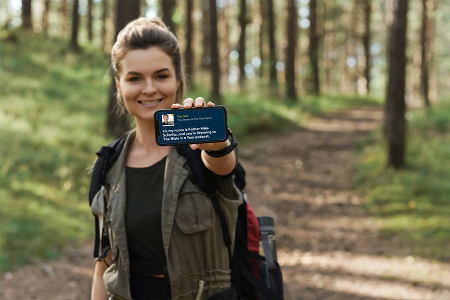 A woman on a trail holding a phone towards the camera