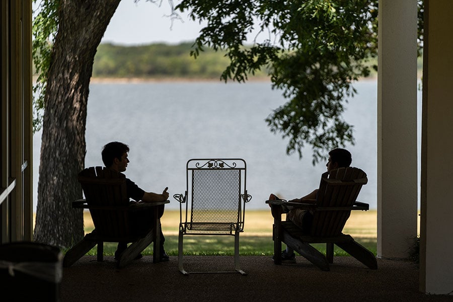 silhouettes of two men at a lake