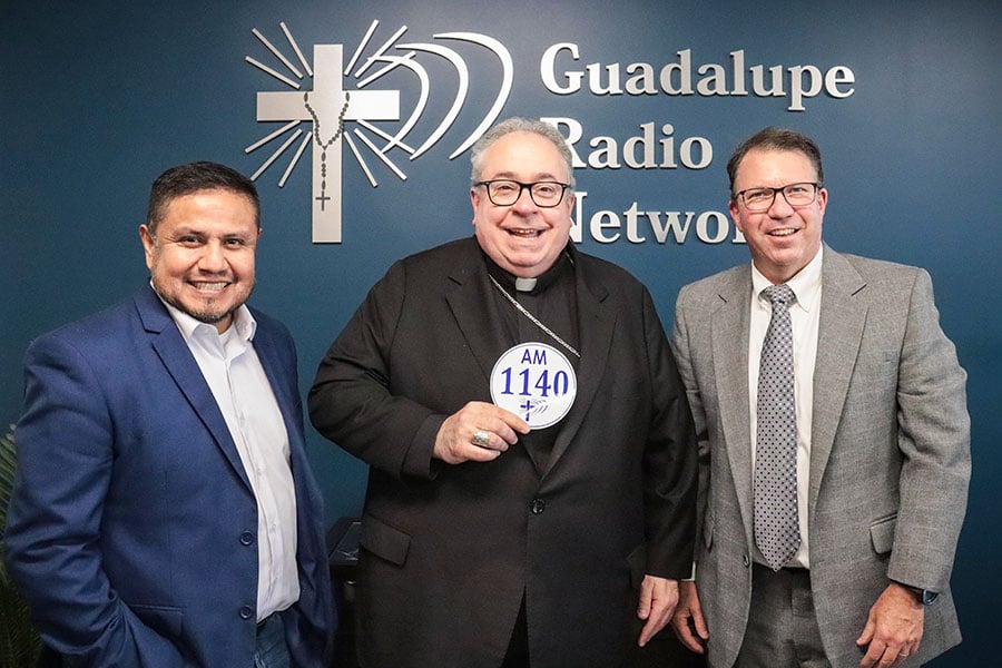 three men in front of logo