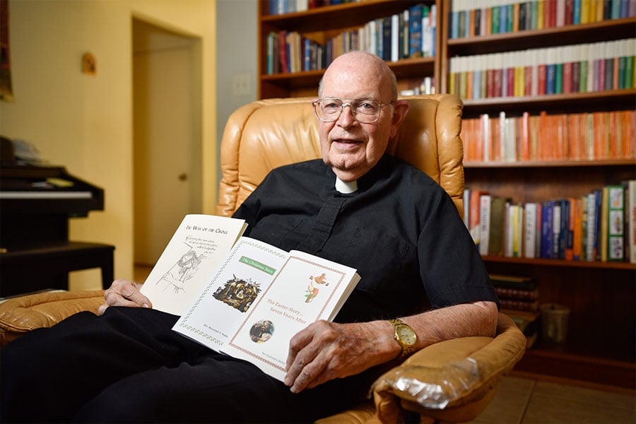 Msgr. Ray Mullan holds some of his writings at his house in Mansfield. (NTC/Ben Torres)