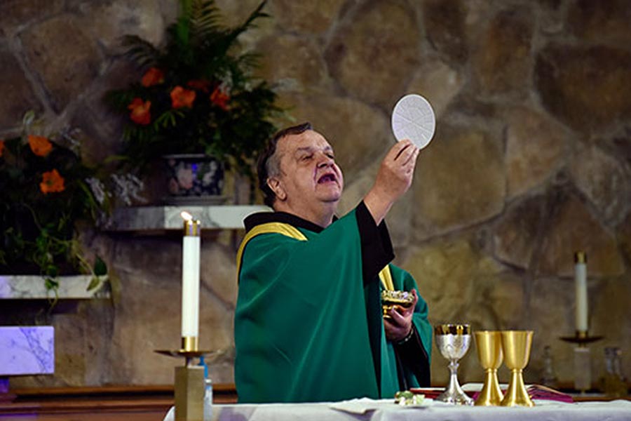 Fr. Robert Sieg holds the Eucharist before Communion.