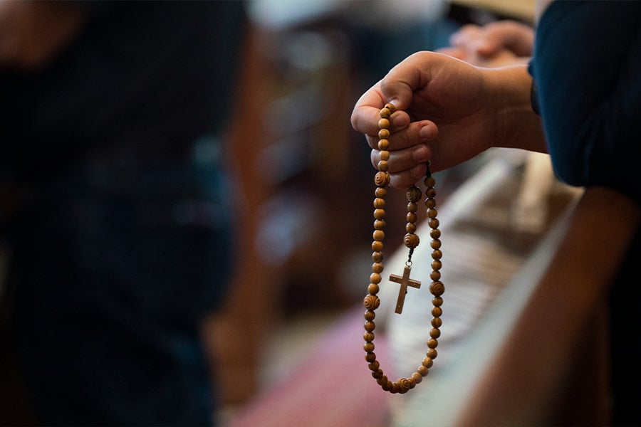 A worshipper holds a rosary during a Mass at St. John Paul II Parish in Denton. (NTC/Juan Guajardo)