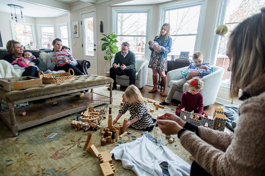 Jennie and Kevin Punswick, pictured at far left and in front of window, pray the rosary with family and friends at their home in Overland Park, Kan., Jan. 12, 2020. Erin and Tom Joerger, Erin on couch, and Samantha O'Malley in foreground at right, were among those who joined them. Baby-holding duty was shared by all, including 10-year-old John Punswick. (CNS photo/Doug Hesse, The Leaven)