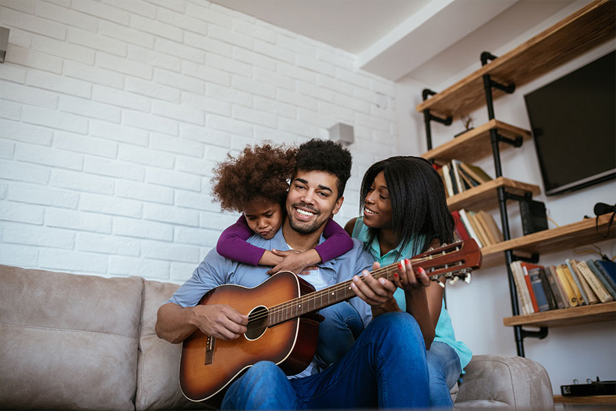 Portrait of an african american family enjoying singing together and playing guitar at home. (bernardbodo)