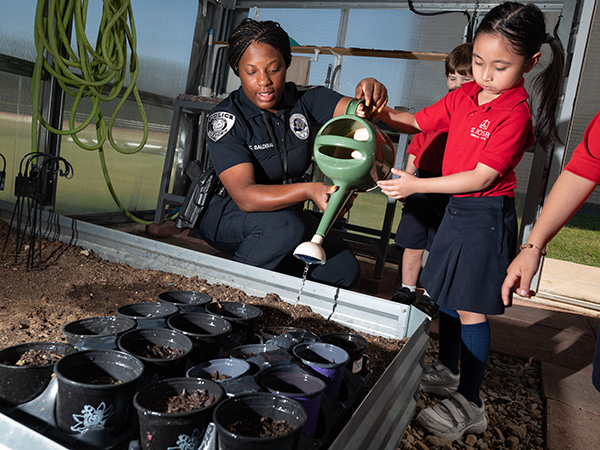police officer helps students in greenhouse