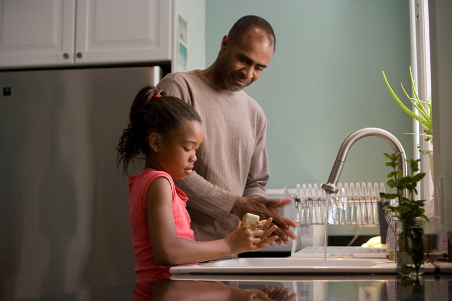 Photo of a father and his daughter doing the dishes. 