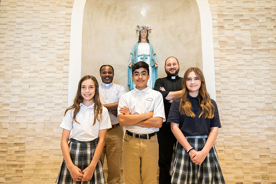 Students pose with Fathers Boniface Muro and Stephen Hauck on May 15, 2023 at St. Martin de Porres Catholic School in Prosper.