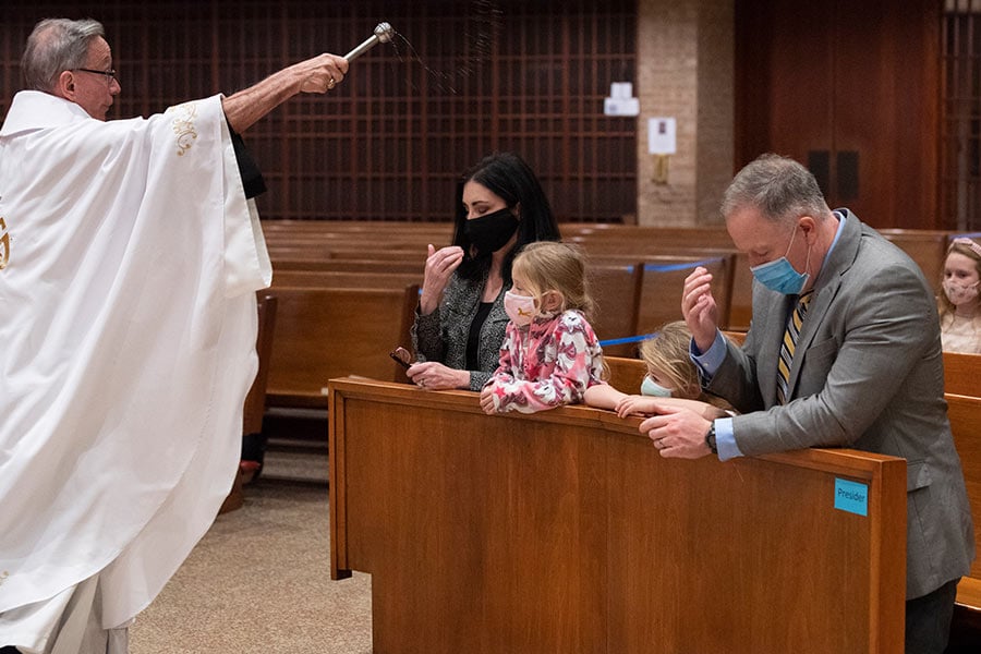 Fr. Jim Gigliotti blesses Doug Allen, right, and his daughters.
